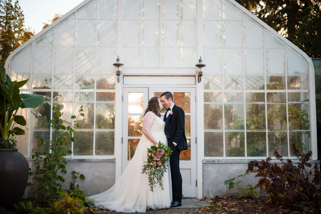 Bride and groom in front of greenhouse